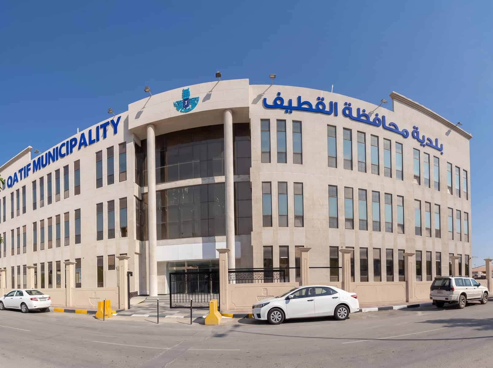 Qatif Municipality building with Arabic and English signage under clear sky.